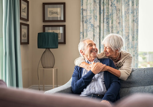 Happy aged couple in their sitting room - evidence of good eye exam