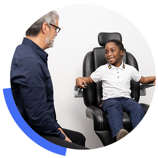 An optometrist wearing glasses smiling at his childhood patient