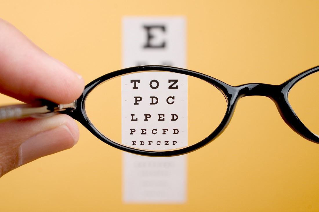 A hand with magnifying glass lens against some selected alphabets