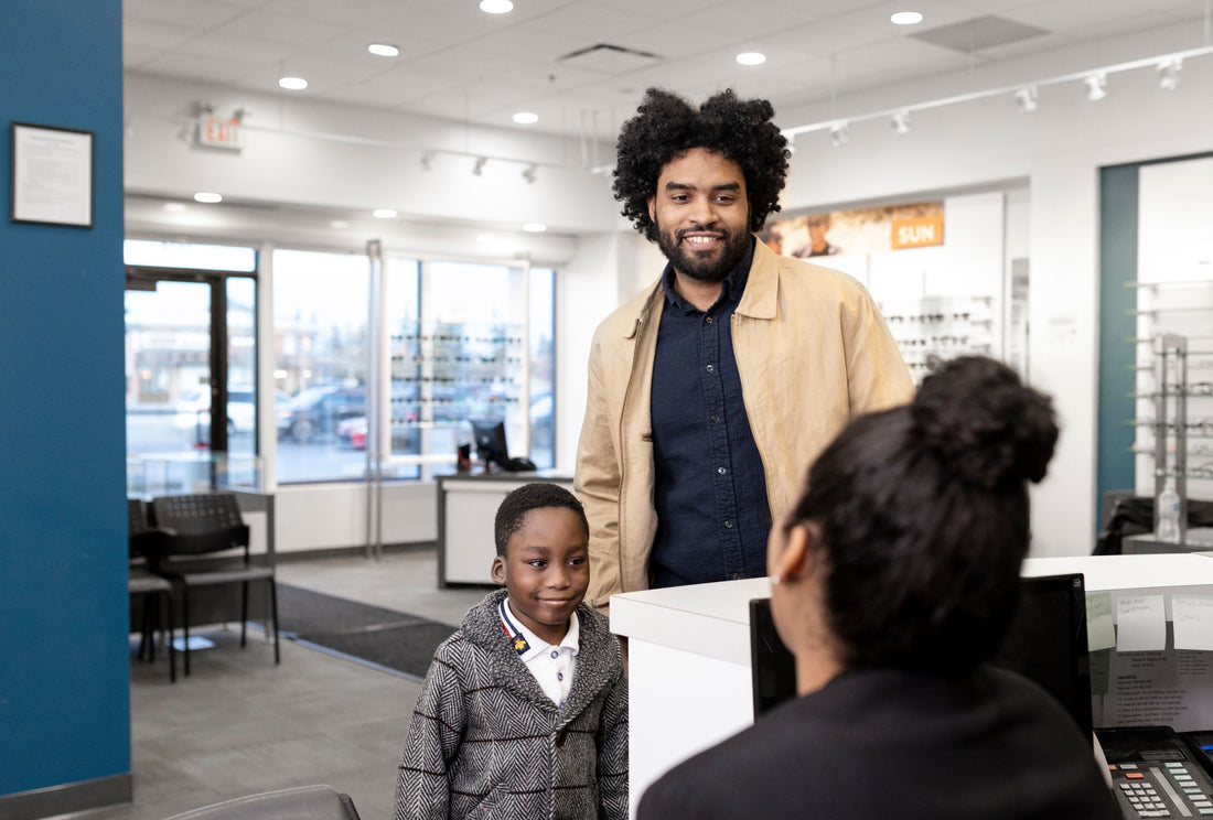 A dad and his son receiving a warm welcome by the receptionist of an eye clinic
