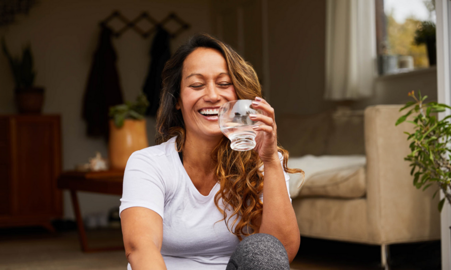 A lady with a glass of cup eyes closed and laughing