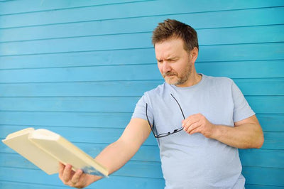A man holding a book afar suffering from Myopia