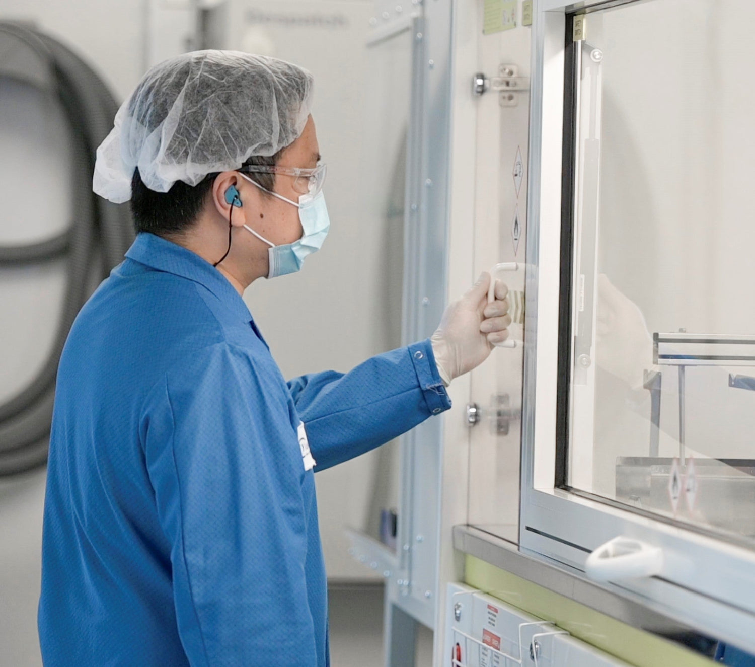The photo of a laboratory worker trying to open a door in the lab. where lenses are manufactured