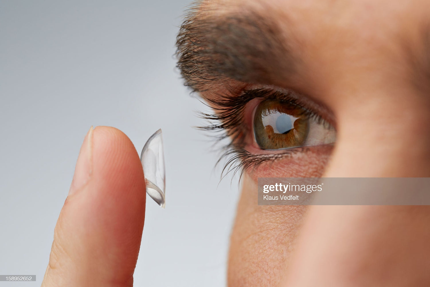 A man with contact lens to his fingers about to wear it