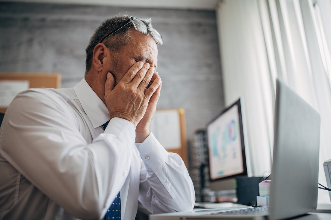Man in office holding face, appearing stressed.