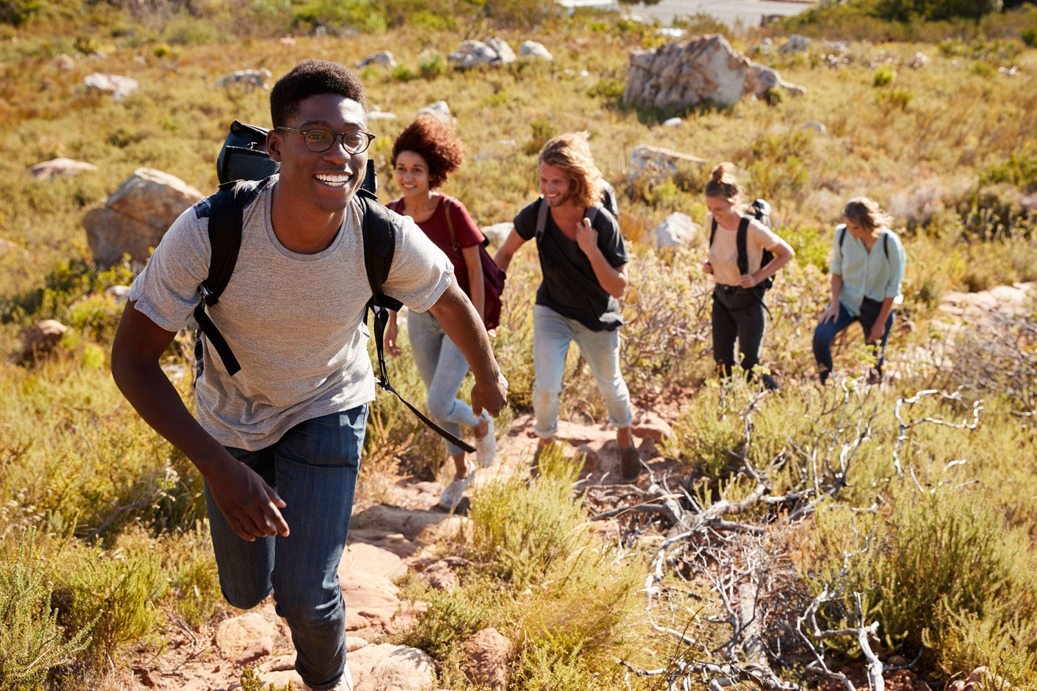 Group of young adults hiking off road. The squad leader got his single vision lenses on and wearing a smile,