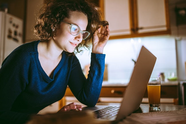 A lady sitting in front of a laptop with specialty lenses on to prevent eye defects