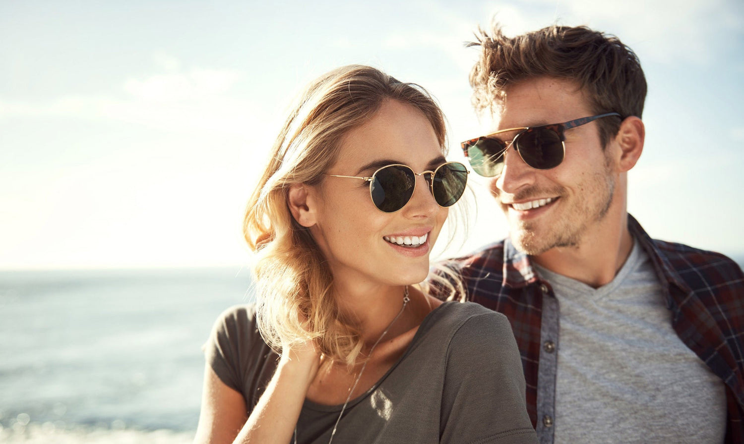 A man and a woman both putting on a pair of Sunglasses